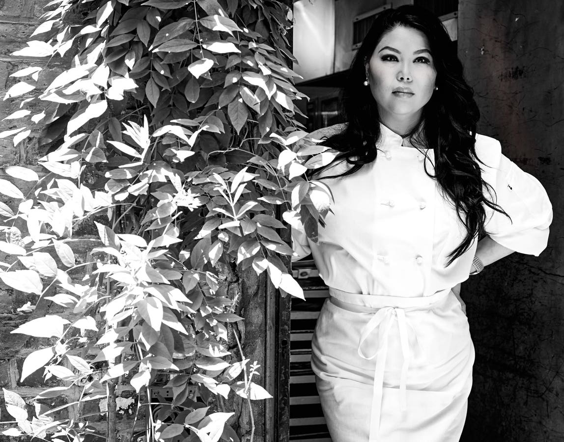 Angie Mar in chef’s whites beside the wisteria at the entrance